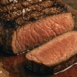 juicy grilled steak resting on wooden cutting board How to Grill the BEST New York Strip Steak of your LIFE