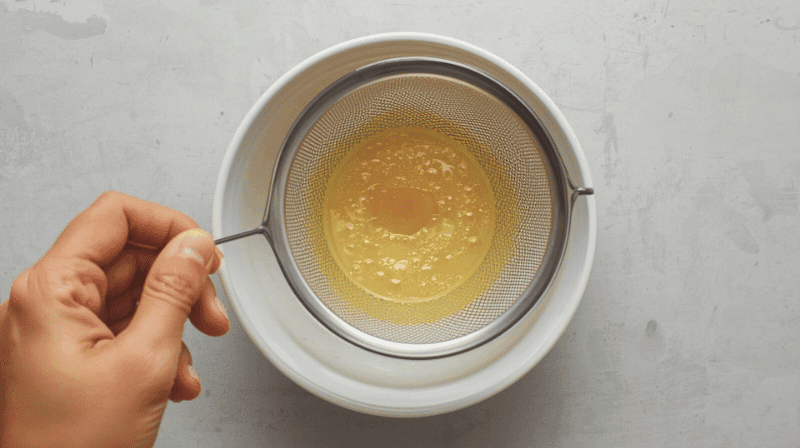 How to strain egg mixture for smooth Chinese steamed custard using a fine-mesh sieve.